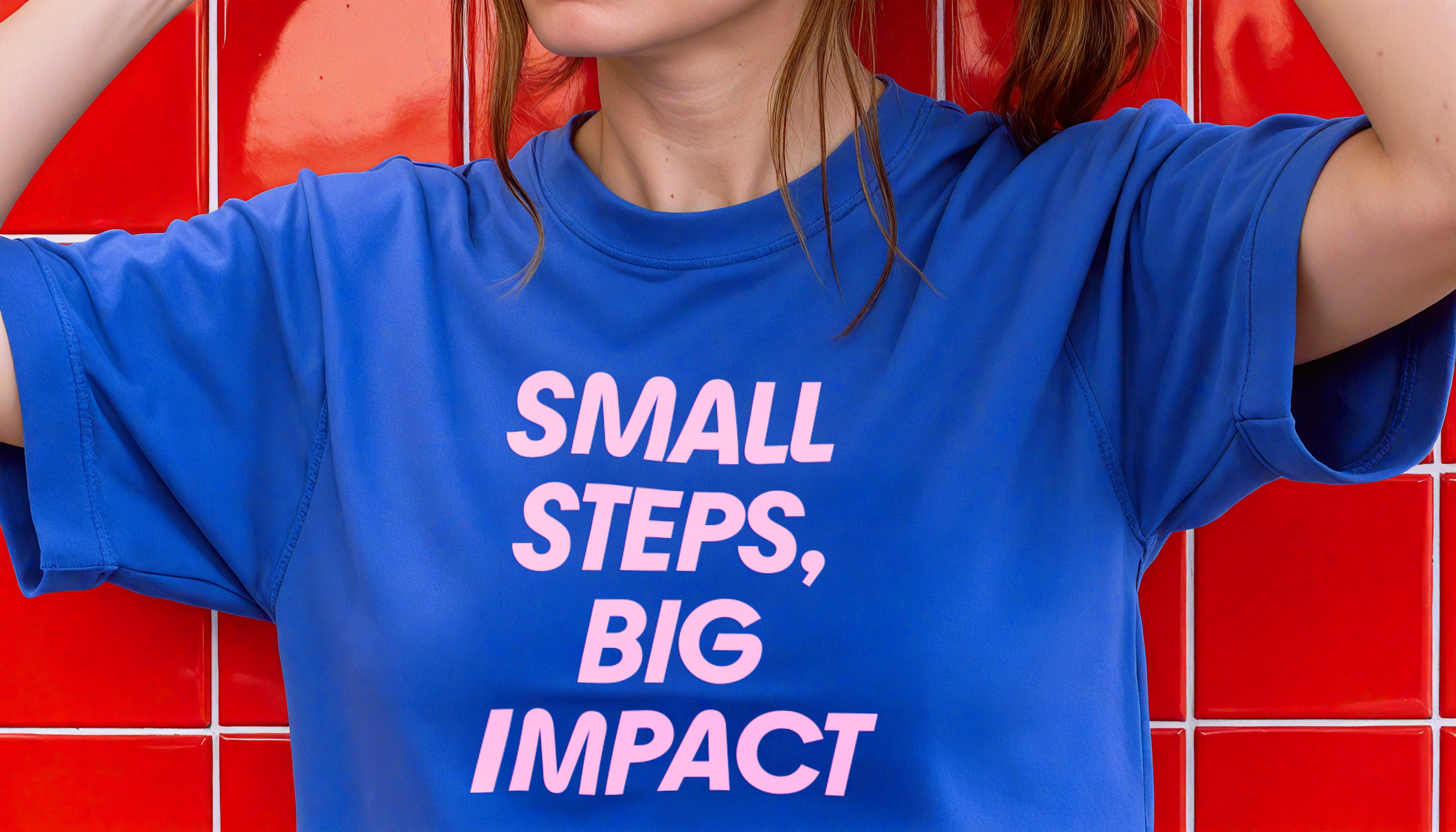 Woman wearing a blue t-shirt with the copy line 'Small steps, big impact'